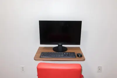 a computer monitor and keyboard on a desk with a red chair at 1Bed 1Bath Apt near EWR, Parking 18 min from Penn St. in Newark