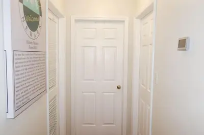 a white door in a hallway with a sign on the wall at 1Bed 1Bath Apt near EWR, Parking 18 min from Penn St. in Newark