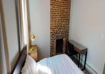 a bedroom with a bed and a desk next to a brick wall at Charming 3BR Apartment in NYC in New York