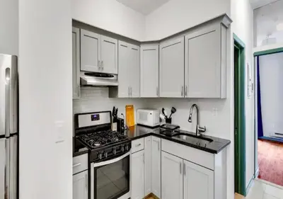 a kitchen with white cabinets and a stove top oven at Charming 3BR Apartment in NYC in New York