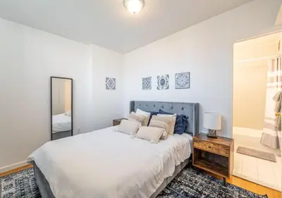 a white bedroom with a large bed and a mirror at Amazing Furnished 1 BR Midtown West in New York