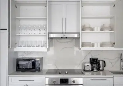 a kitchen with white cabinets and a microwave at 3BR Furnished Loft in Midtown West in New York
