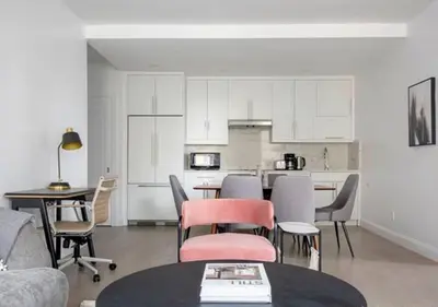 a living room with a table and chairs and a kitchen at 3BR Furnished Loft in Midtown West in New York