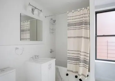 a white bathroom with a sink and a shower curtain at 3BR Furnished Loft in Midtown West in New York