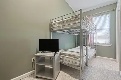 a bedroom with a bunk bed with a television and a desk at Suites On Chocolate - The School in Hershey