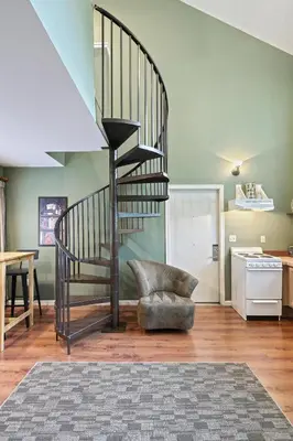 a spiral staircase in a living room with a chair at Suites On Chocolate - The School in Hershey