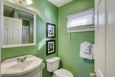 a green bathroom with a toilet and a sink at Suites On Chocolate - The Club in Hershey
