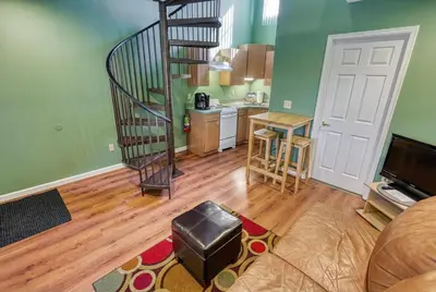 a living room with a spiral staircase and a kitchen at Suites On Chocolate - The Club in Hershey
