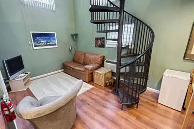 a living room with a spiral staircase and a couch at Suites On Chocolate - The Zoo in Hershey