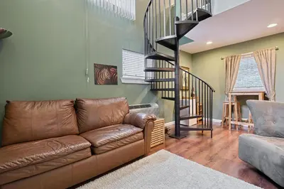 a living room with a couch and a spiral staircase at Suites On Chocolate - The Zoo in Hershey