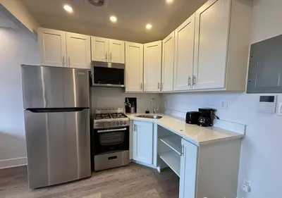 a kitchen with white cabinets and a stainless steel refrigerator at Close to Times Square! Stunning Studio in NYC! in New York