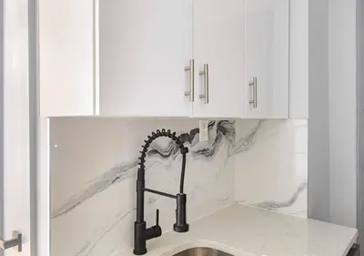 a kitchen counter with a sink and white cabinets at Midtown West 2 Bedroom Furnished Apartment Rental in New York