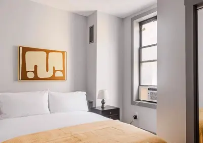 a white bedroom with a bed and a window at Midtown West 2 Bedroom Furnished Apartment Rental in New York