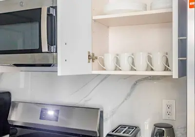 a kitchen with white cabinets with mugs and a microwave at Midtown West 2 Bedroom Furnished Apartment Rental in New York