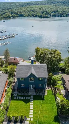 an aerial view of a blue house on the water at Lakeview Villa with Private Hot Tub, Firepit & Breathtaking Cliff Views in Greenwood Lake