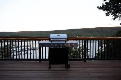 a barbecue grill on a deck with a view of the water at Lakeview Villa with Private Hot Tub, Firepit & Breathtaking Cliff Views in Greenwood Lake
