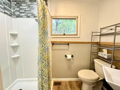 a bathroom with a toilet and a window and a shower at Cayuga lake cottage with private lake access in Washingtonville