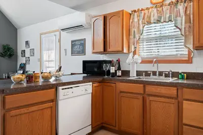 a kitchen with wooden cabinets and a white dishwasher at Hot Tub Fire-place Game Room Arrowhead Lake in Thornhurst