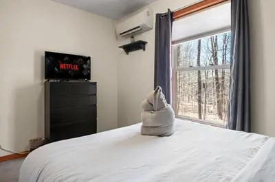 a stuffed animal sitting on a bed looking out a window at Hot Tub Fire-place Game Room Arrowhead Lake in Thornhurst