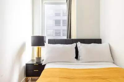 a bedroom with a bed with white pillows and a window at Blueground Midtown S gym roof nr Times Sq NYC-1776 in New York