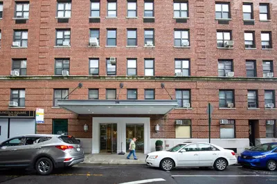 a woman walking in front of a brick building at UWS 2br w wd doorman gym nr Central Park NYC-1082 in New York