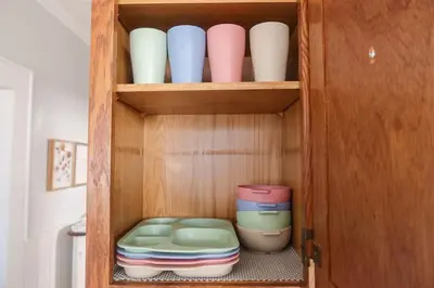 a cupboard with bowls and plates in it at Cozy 2BR 5min to NYC Train and 10min to Seton Hall in West Orange