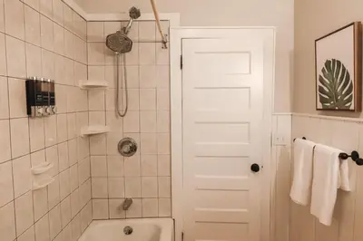 a bathroom with a shower and a white door at Cozy 2BR 5min to NYC Train and 10min to Seton Hall in West Orange