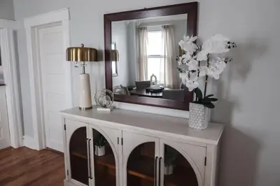 a vanity with a mirror and a vase of flowers at Cozy 2BR 5min to NYC Train and 10min to Seton Hall in West Orange
