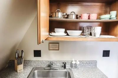 a kitchen counter with a sink and a shelf with dishes at Cozy Attic Studio for 2 5min to NYC Train Station in West Orange
