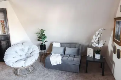 a living room with a couch and a chair at Cozy Attic Studio for 2 5min to NYC Train Station in West Orange