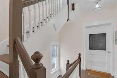 a staircase in a home with white walls and wood floors at Cozy Attic Studio for 2 5min to NYC Train Station in West Orange
