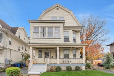 a white house with a porch at Cozy Attic Studio for 2 5min to NYC Train Station in West Orange