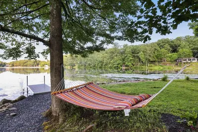 a hammock hanging from a tree next to a lake at Lakeside Haven, a Modern Cottage with Lake Views in Effort