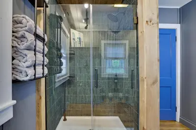 a shower with a glass door in a bathroom at Lakeside Haven, a Modern Cottage with Lake Views in Effort