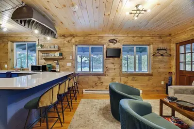 a kitchen and living room with a bar and chairs at Lakeside Haven, a Modern Cottage with Lake Views in Effort