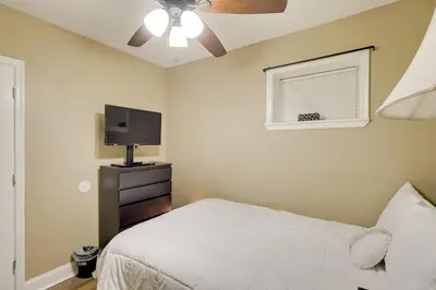 a bedroom with a bed with a ceiling fan and a television at 1 Mi to Dtwn Wilmington Convenient and Cozy Home! in Wilmington