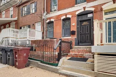a brick house with a black door and a trash can at 1 Mi to Dtwn Wilmington Convenient and Cozy Home! in Wilmington
