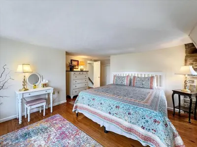 a bedroom with a bed and a table and a mirror at The White House by Leavetown Vacations in Wrightsville