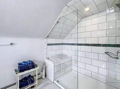 a white bathroom with a shower with a glass door at The White House by Leavetown Vacations in Wrightsville