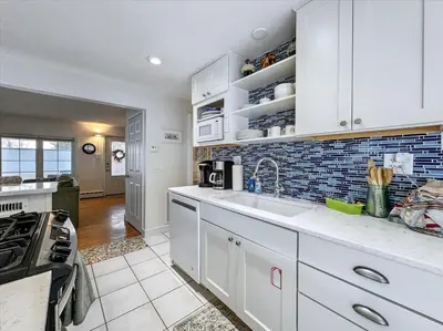 a kitchen with white cabinets and a sink at The White House by Leavetown Vacations in Wrightsville
