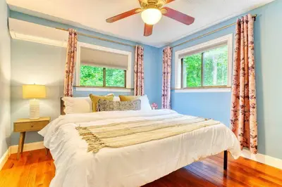 a bedroom with a large bed and two windows at Grand Woodland Retreat - Hot Tub - Game Room in Gouldsboro