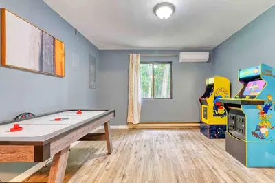 a room with a ping pong table and a video game at Grand Woodland Retreat - Hot Tub - Game Room in Gouldsboro