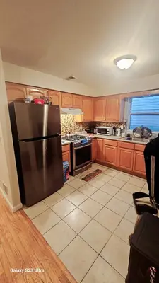 a kitchen with a stainless steel refrigerator and wooden cabinets at Divine Villa and Resort - 32 Evergreen in Newark