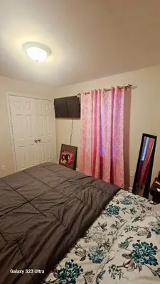 a bedroom with a large bed and pink curtains at Divine Villa and Resort - 32 Evergreen in Newark