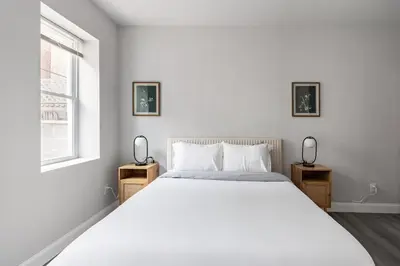 a bedroom with a large white bed and two windows at Philly Getaway - Chic Stay Near Center City in Philadelphia