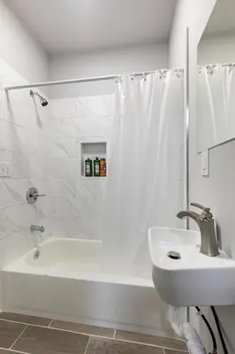 a white bathroom with a sink and a bath tub at Philly Getaway - Chic Stay Near Center City in Philadelphia