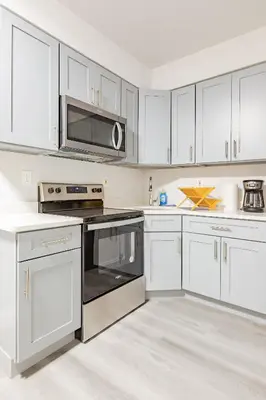 a white kitchen with stainless steel appliances and white cabinets at Philly Getaway - Chic Stay Near Center City in Philadelphia