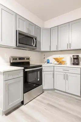 a kitchen with white cabinets and black appliances at Philly Getaway - Chic Stay Near Center City in Philadelphia
