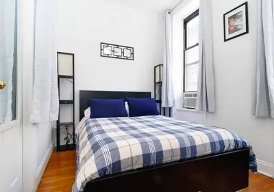 a bedroom with a bed with a blue and white plaid blanket at Outdoor Space Washer Dryer Dishwasher 3Beds Apt, June to Aug 90 days stay required in New York