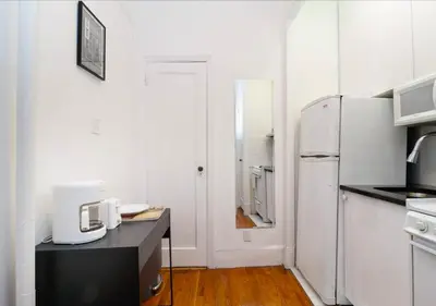 a white kitchen with a refrigerator and a table at Outdoor Space Washer Dryer Dishwasher 3Beds Apt, June to Aug 90 days stay required in New York